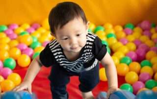 Young child climbing in a colorful sensory ball pit during an occupational therapy session at OrbRom Center in Phnom Penh