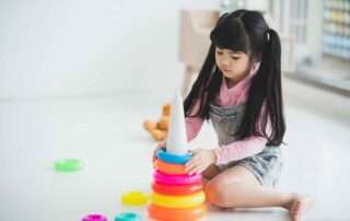 Young girl stacking colorful rings to improve visual-motor skills during occupational therapy at OrbRom Center in Phnom Penh