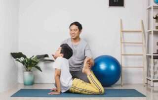 Child stretching with support from a therapist during occupational therapy session at OrbRom Center in Phnom Penh.