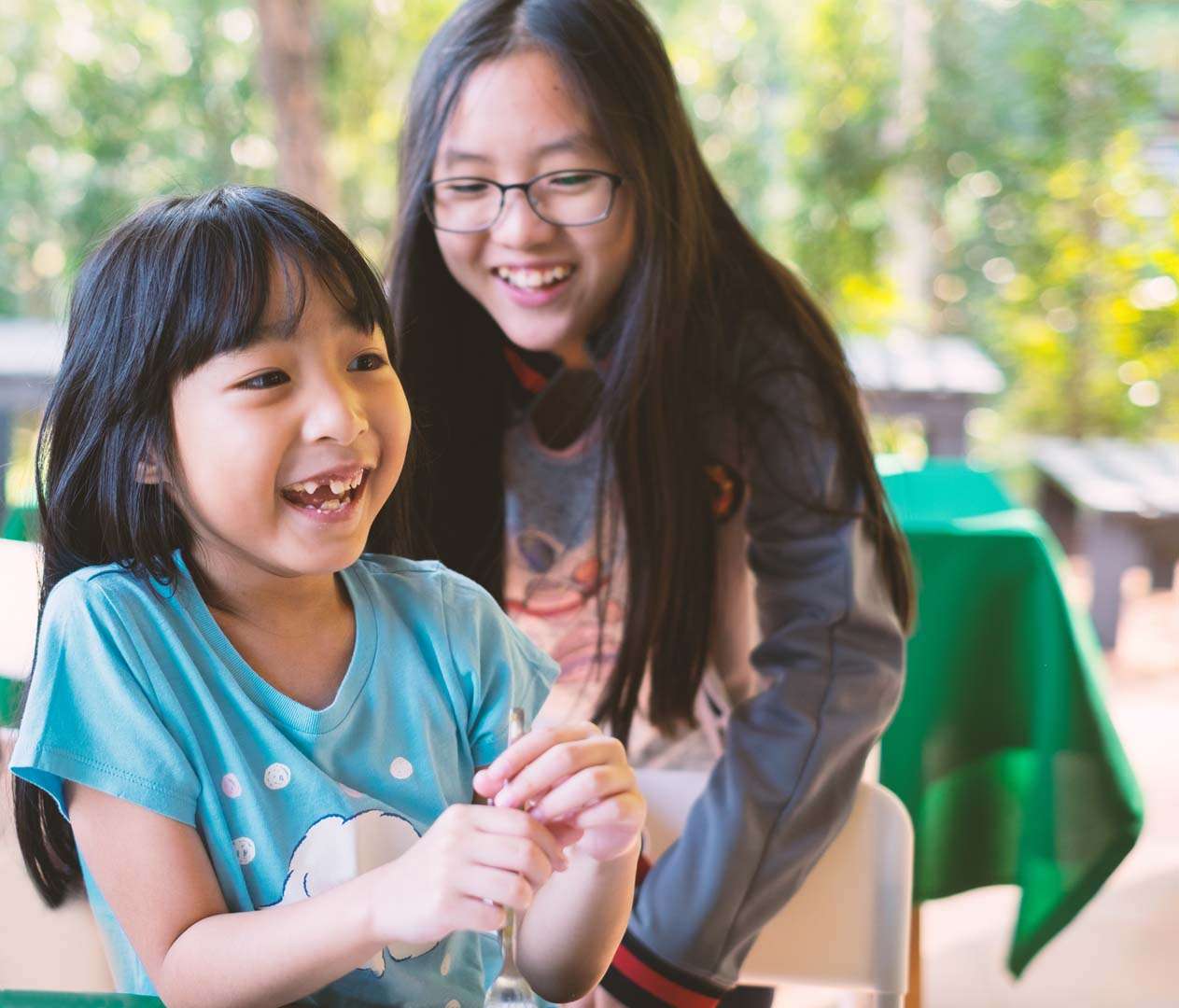Two young girls smiling and interacting together—illustrating how peer relationships can support speech and social communication development.