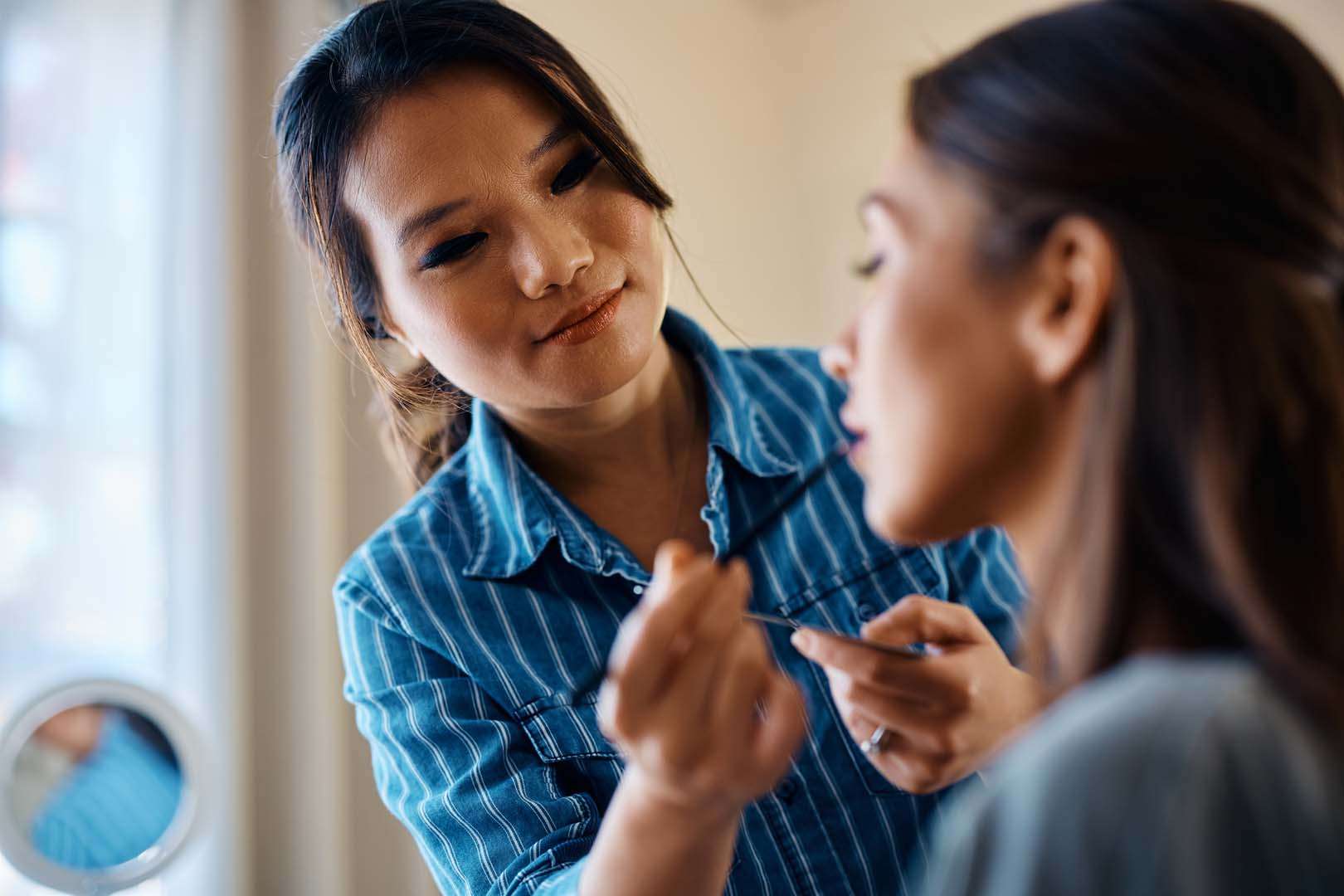 A focused woman applying makeup while maintaining eye contact—illustrating the role of nonverbal cues like facial expressions and gestures in communication.