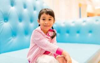 Young girl sitting calmly and confidently on a blue sofa, symbolizing self-expression and emotional readiness in special needs education