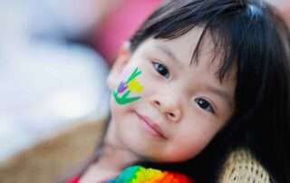 Young girl with flower face paint, gazing gently—symbolizing creative expression and emotional connection.