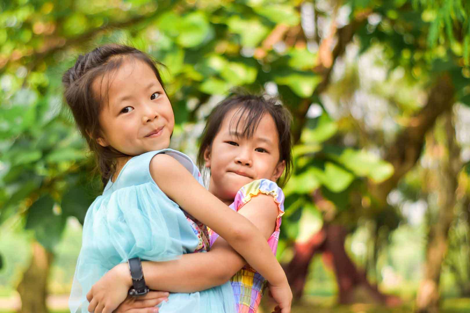 Two young girls smiling and waving during an online class, engaging in social learning and virtual interaction at home